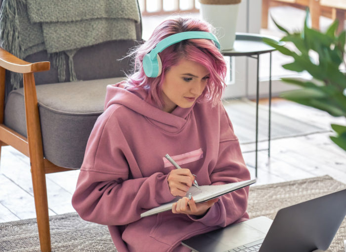 Schülerin mit Kopfhörer die sich Notizen macht