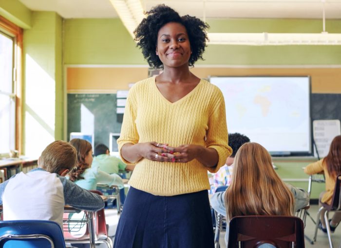Leherin in gelben Pullover im Klassenzimmer mit Schulkindern