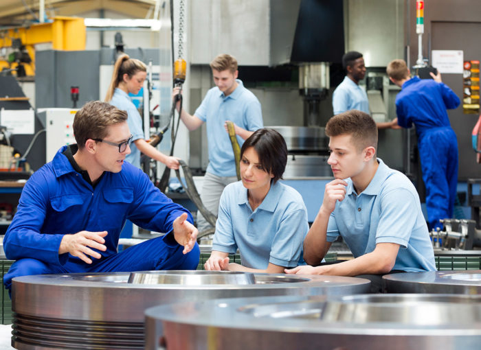 Azubis die in einem Betrieb etwas erklärt bekommen vom Ausbildungsleiter