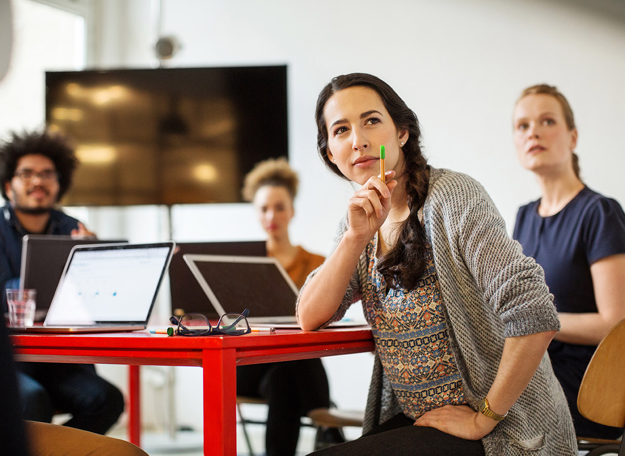 Lehrerin am Tisch die sich umdreht und auf etwas schaut