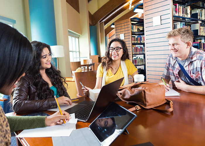 Gruppe von Schülern im Austausch am Tisch in einer Bibliothek
