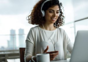Schülerin mit Kopfhörern am PC in einem Meeting
