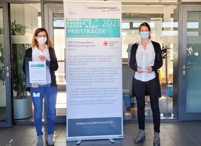 Schulewirtschaft Preisträger 2021 mit Urkunde vor Firmenzentrale des DRK Mittelhessen