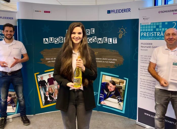 Schulewirtschaft Preisträger mit Urkunde, Preis und Sekt in der Hand