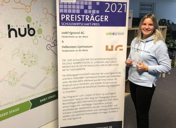 Junge Frau vor einem Banner zum Schulewirtschaft Preis 2021
