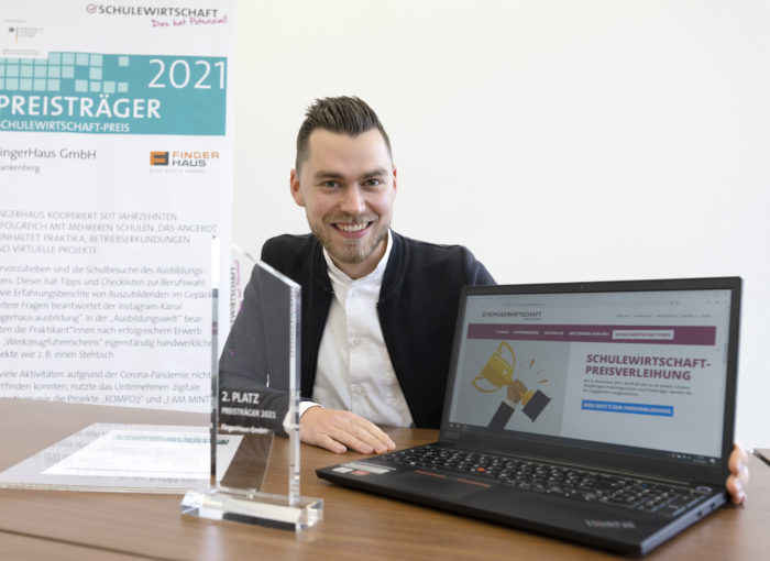 Schulewirtschaft Preisträger 2021 am Tisch mit Laptop und Preis