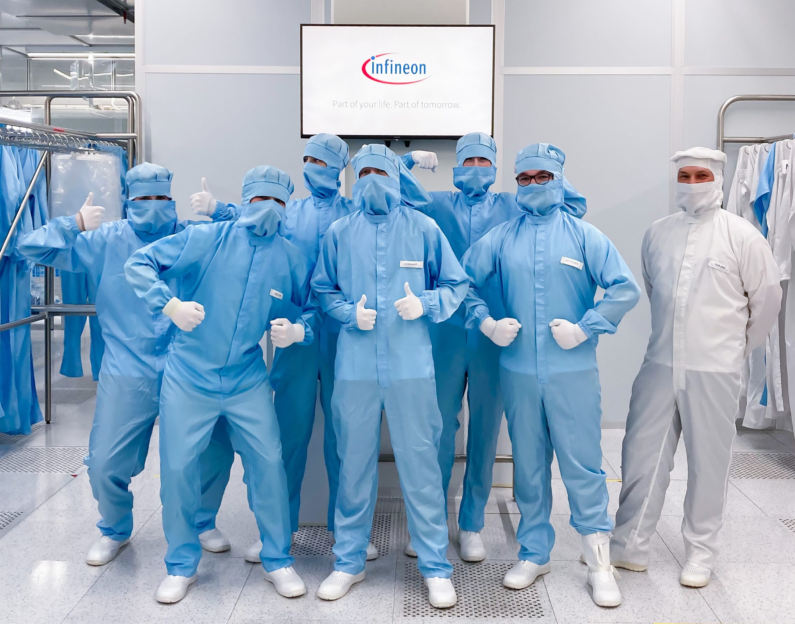 Eine Gruppe Schüler gekleidet in blauen Schutzanzügen zu Besuch bei Infineon in Dresden