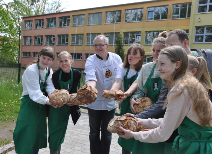 SCHULEWIRTSCHAFT Preisträger Bäckerei Gnauck - Bäckermeister und junge Menschen präsentieren Brotlaibe