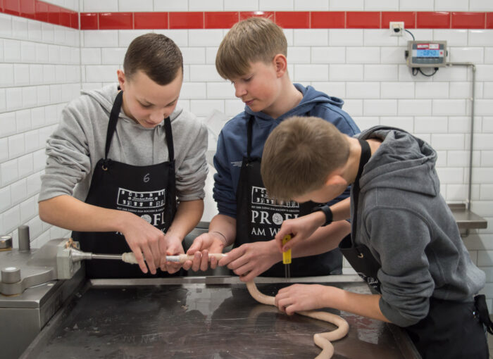 SCHULEWIRTSCHAFT Preisträger Fleischerei Richter - drei junge Männer befüllen Würste