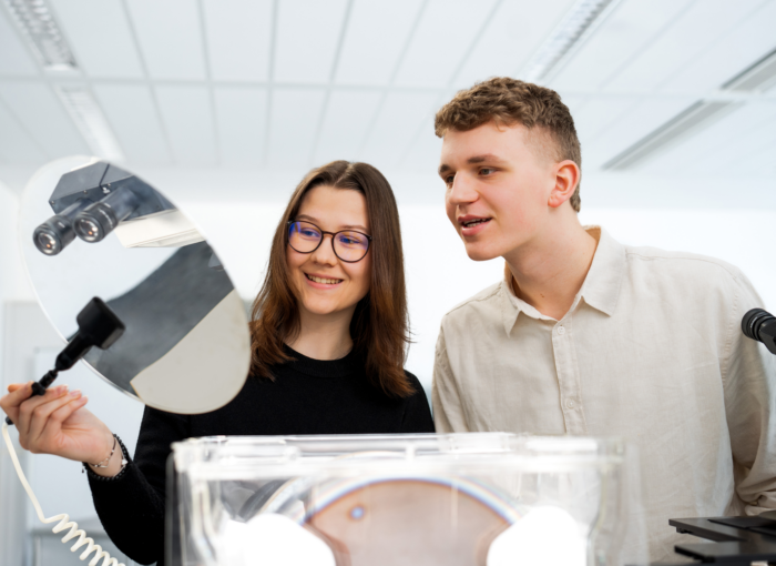 SCHULEWIRTSCHAFT Preisträger Infineon (Dresden) - Junge Frau hält einen Silizium-Waver, den ein junger Mann betrachtet